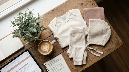 Organic cotton baby clothes arranged on wooden table